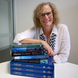 Woman wearing white shirt in front of stack of blue books