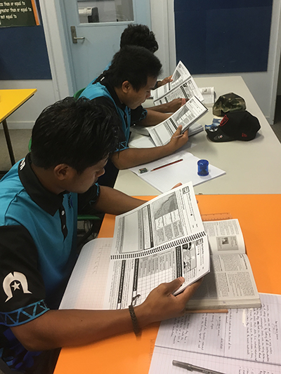 Three students studying from marine science workbook