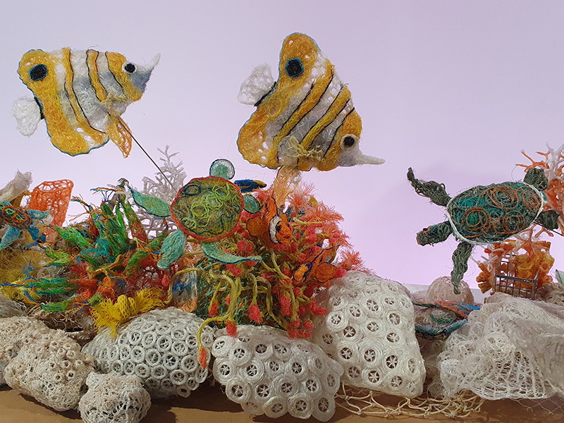 coral reef scene with fish, coral and turtle made from ghost net