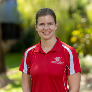 Woman wearing red shirt standing in front of green trees