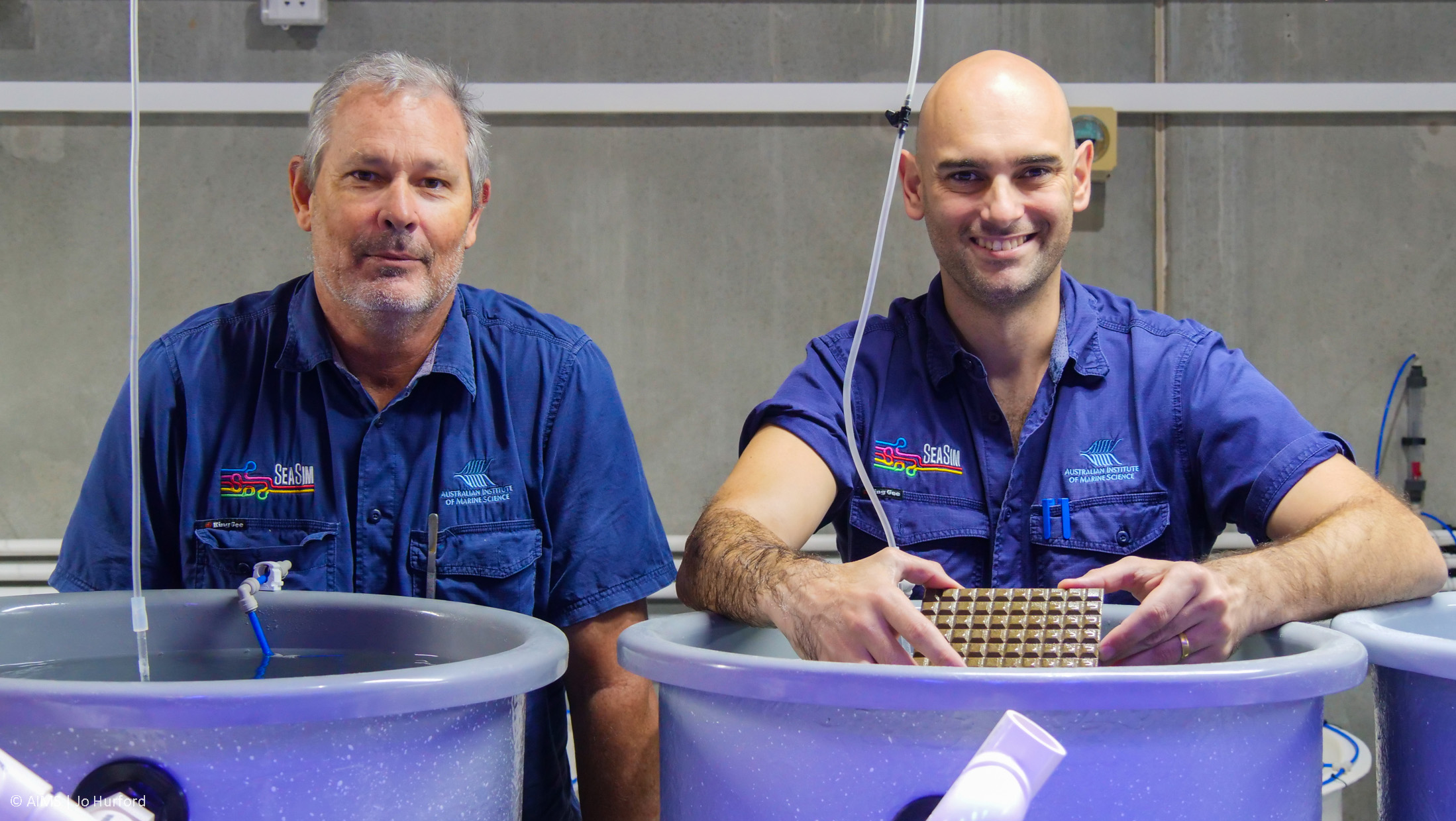 Two aquarium technicians behind giant tubs