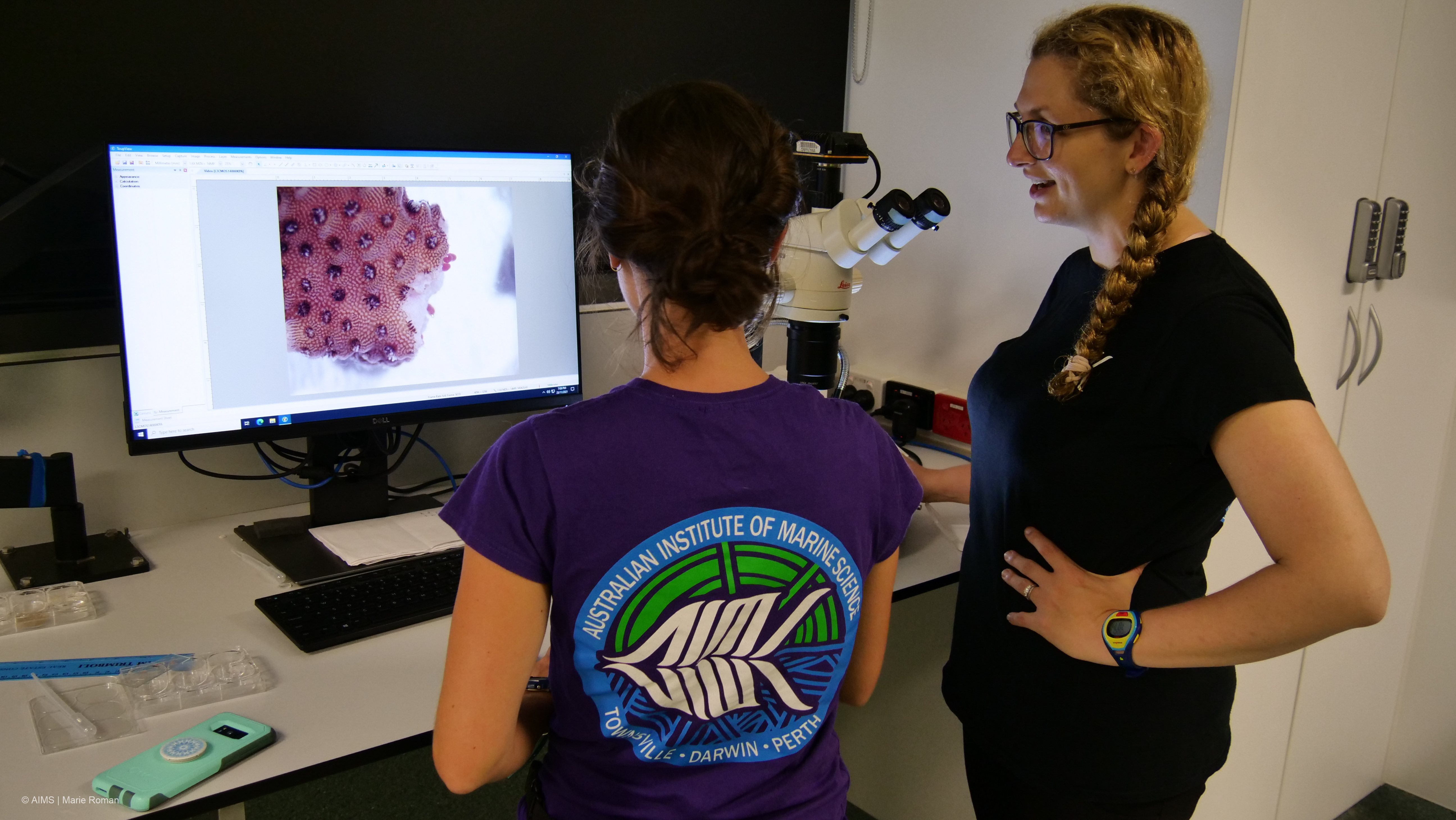 Two women look at a closeup image of a coral colony