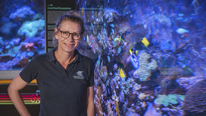 Woman stands next to a reef tank