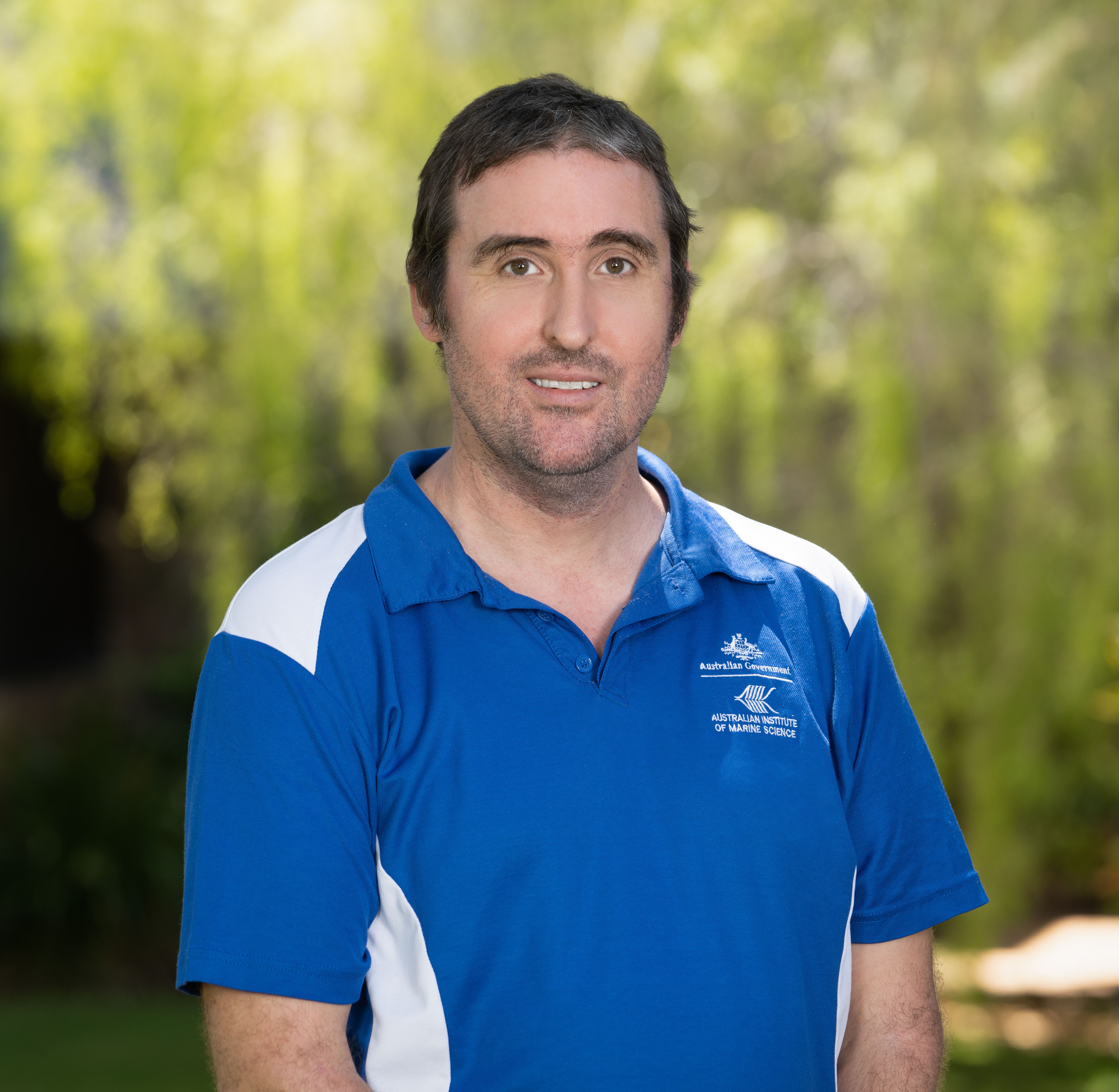 Photo of Paul Rigby wearing a blue shirt with an AIMS logo.