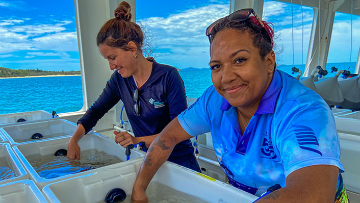 women scientists tend to corals in tubs onboard a research vessel