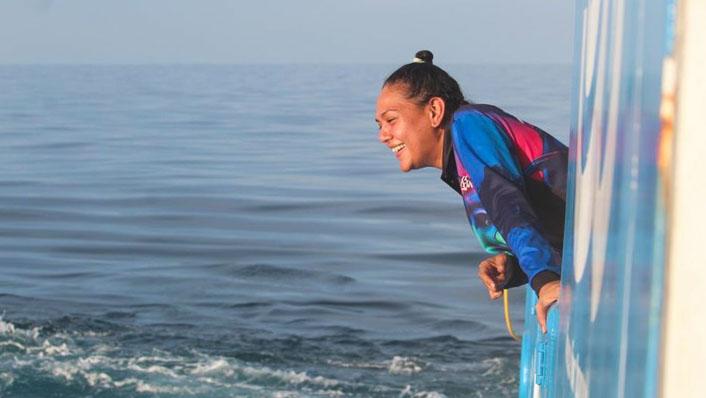 Indigenous woman leans over the side of a vessel at sea