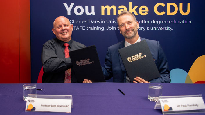 Two men hold signed document to formalise a partnership