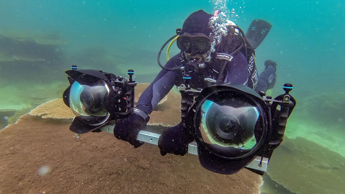 Scuba diver holds a bar with a camera on each end.