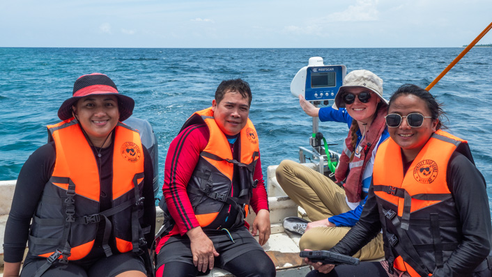 People sit in a small vessel with ReefScan transom attached to the stern