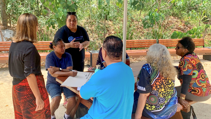 A group stand and sit around a table