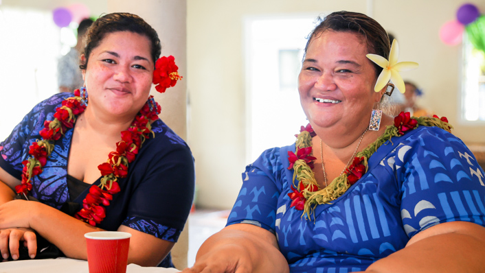 two people smiling in traditional dress with flowers behind their ears