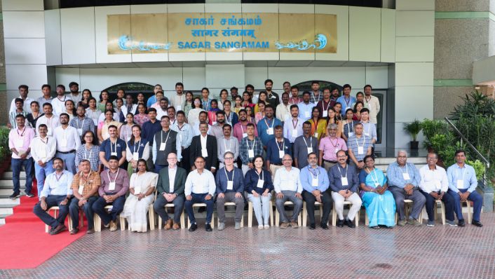 a formal group photo of more than 50 people at a workshop. the delegates are on tiered stands