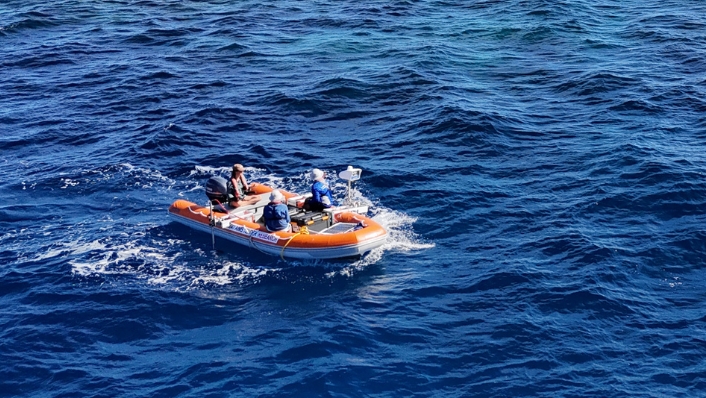 Aerial shot of scientists in a tender boat with a robot