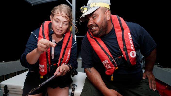 Scientists look at a tube on a boat at night
