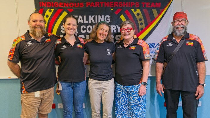 five individuals smiling for the camera in front of a banner that says Indigenous Partenrships Team 