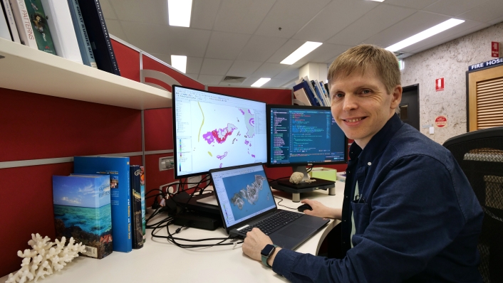 Dr Eric Lawrey at his desk with new reef maps on screen