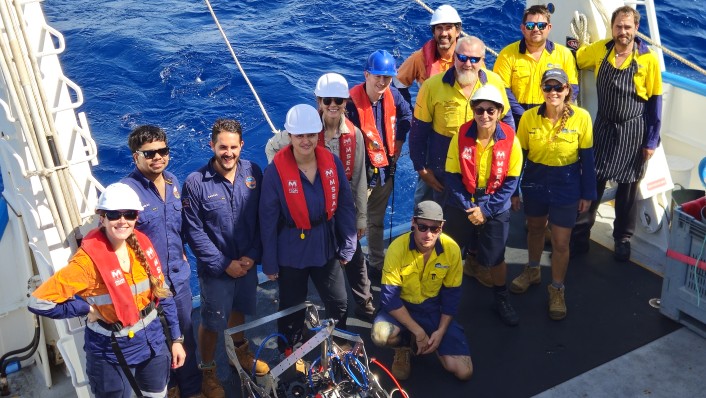 A group shot of people in work wear on the deck of a large boat