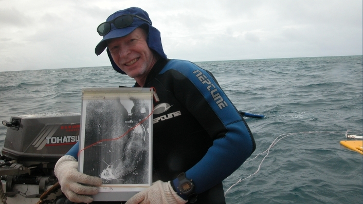 Marine scientist on boat holding up map of reef