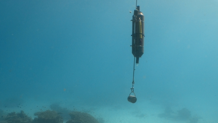 Niskin bottle underwater over coral reef