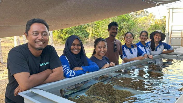 Marine scientists pose around a coral aquaculture system