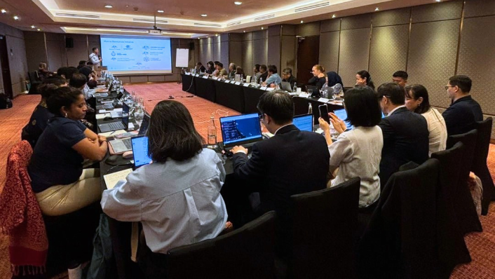 Delegates sit around conference table watching presentation at ReefCloud launch in Kuala Lumpur, Malaysia