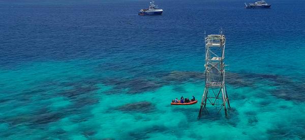 tall metal tower standing up out of the water on top of a reef