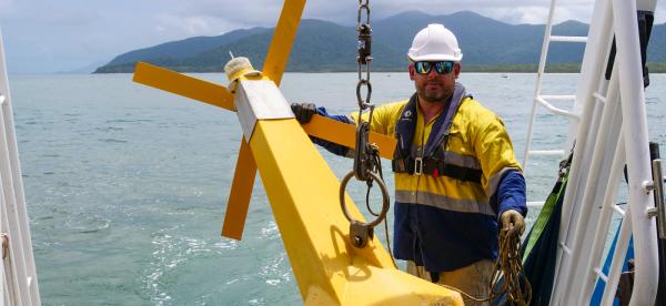 Person in safety gear with large oceanic buoy on the back deck of large vessel