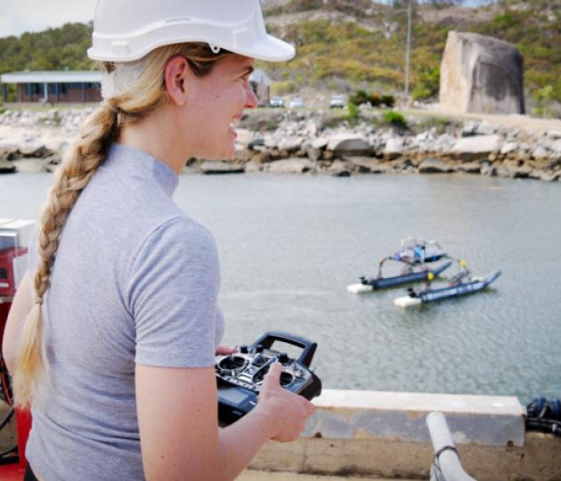 Person with helmet and remote control with large surface drone in background