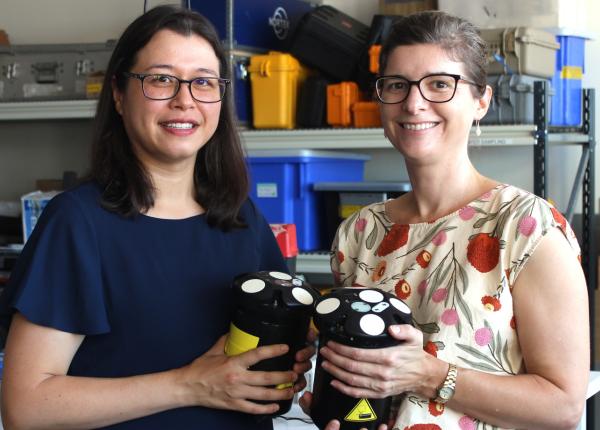 Two women hold devices that measure ocean currents