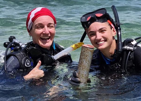 Two divers at the surface smiling and holding equipment that measure light