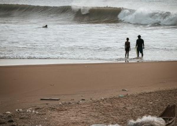 silhouette of two people on beach with rubbish in the foreground