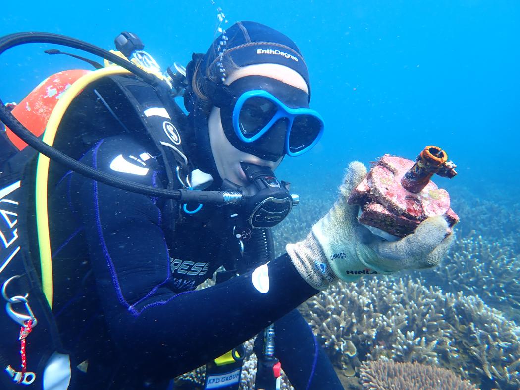Diver underwater looks at device in hand