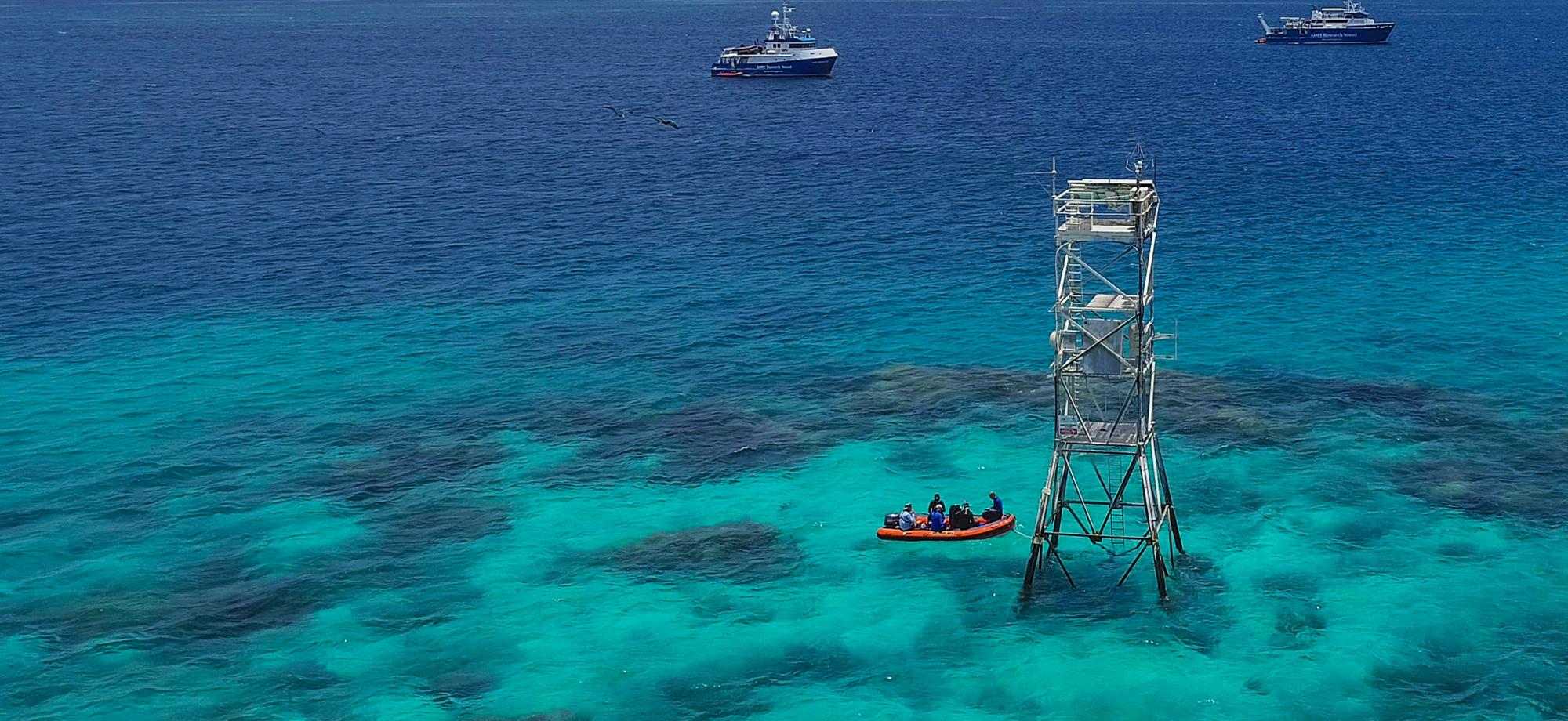 tall metal tower standing up out of the water on top of a reef