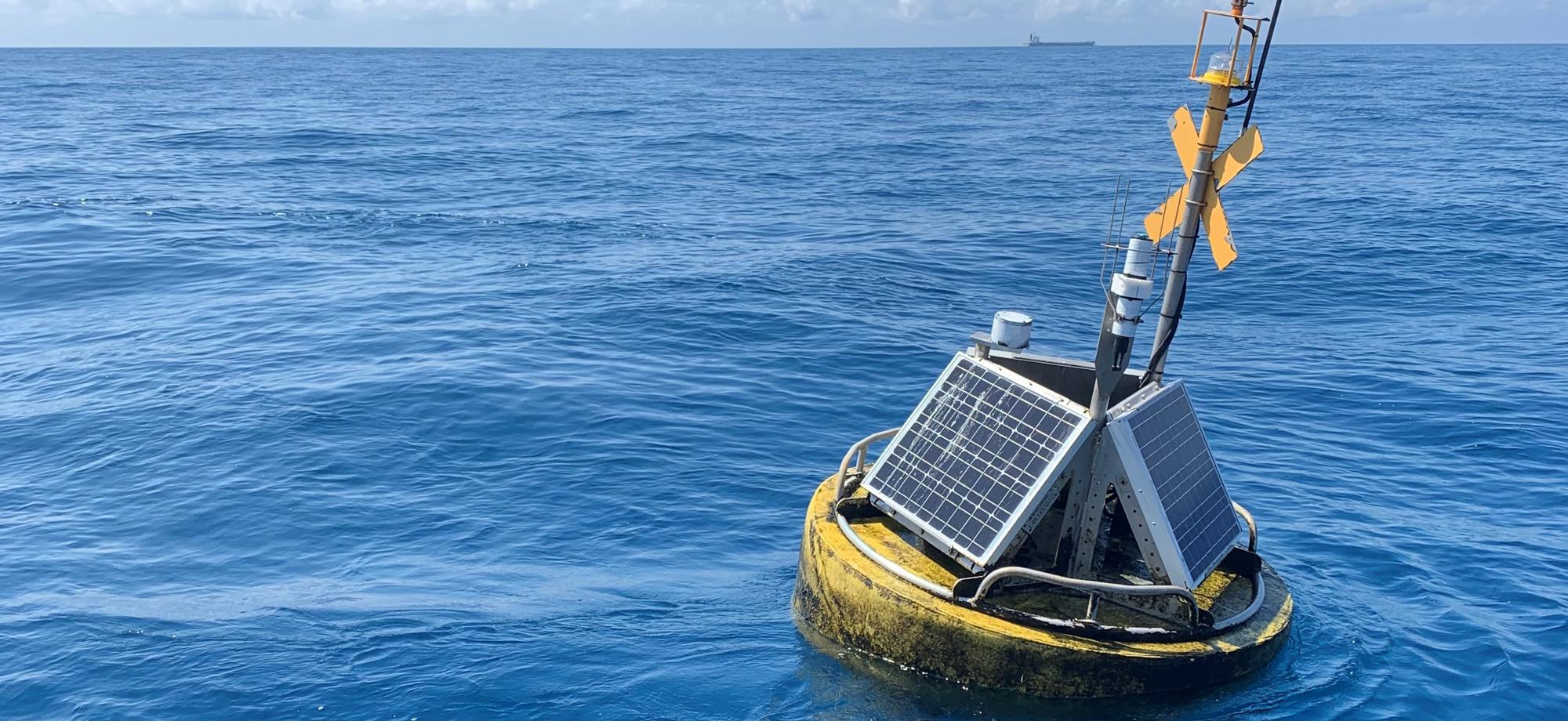 a yellow buoy with solar panels floats on a calm sea