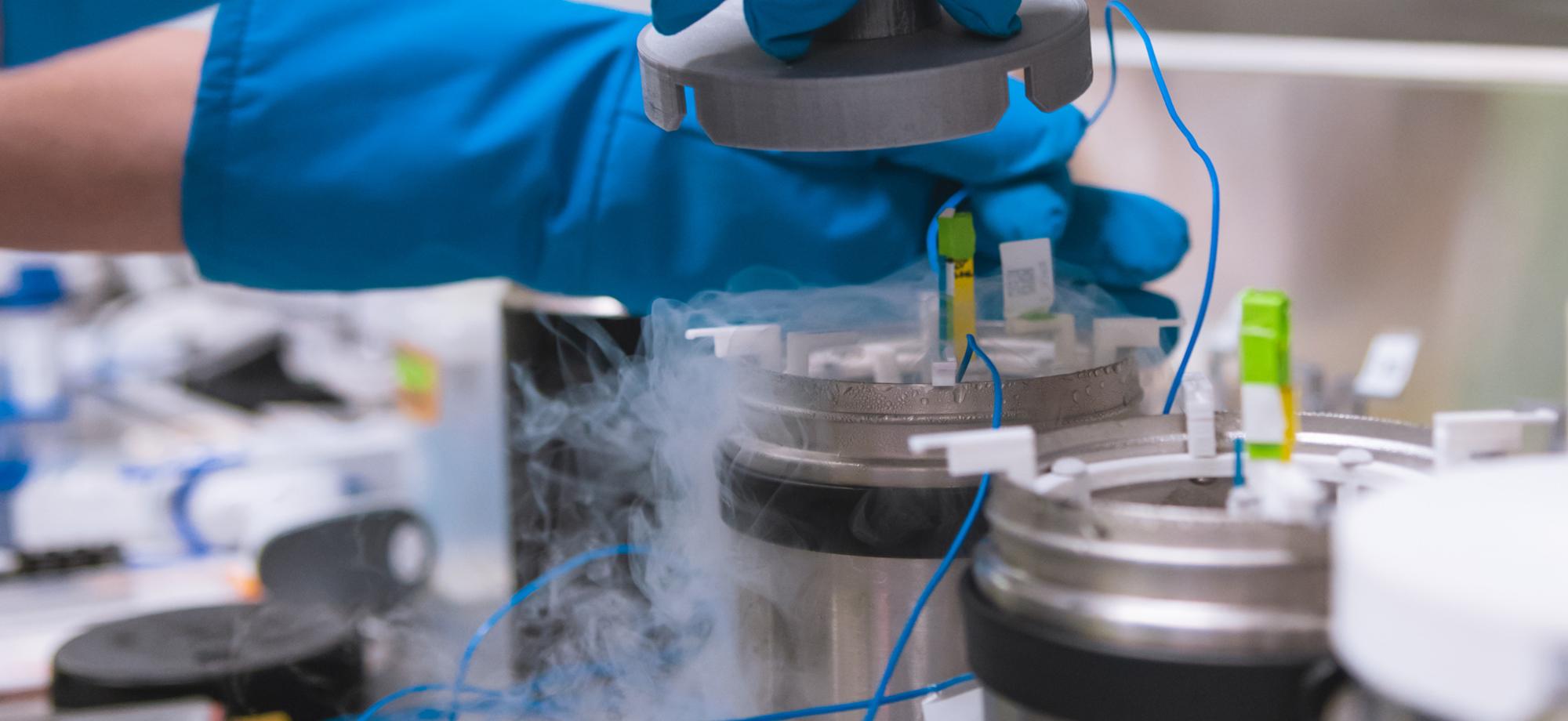 a hand with blue glove holds a science tool over a cannister