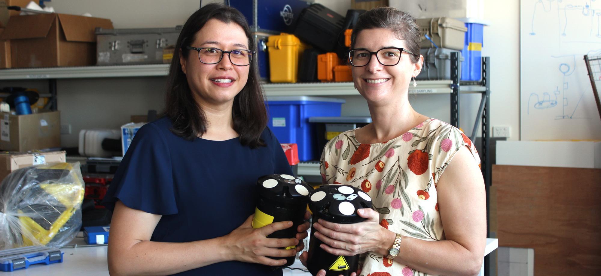 Two women hold devices that measure ocean currents