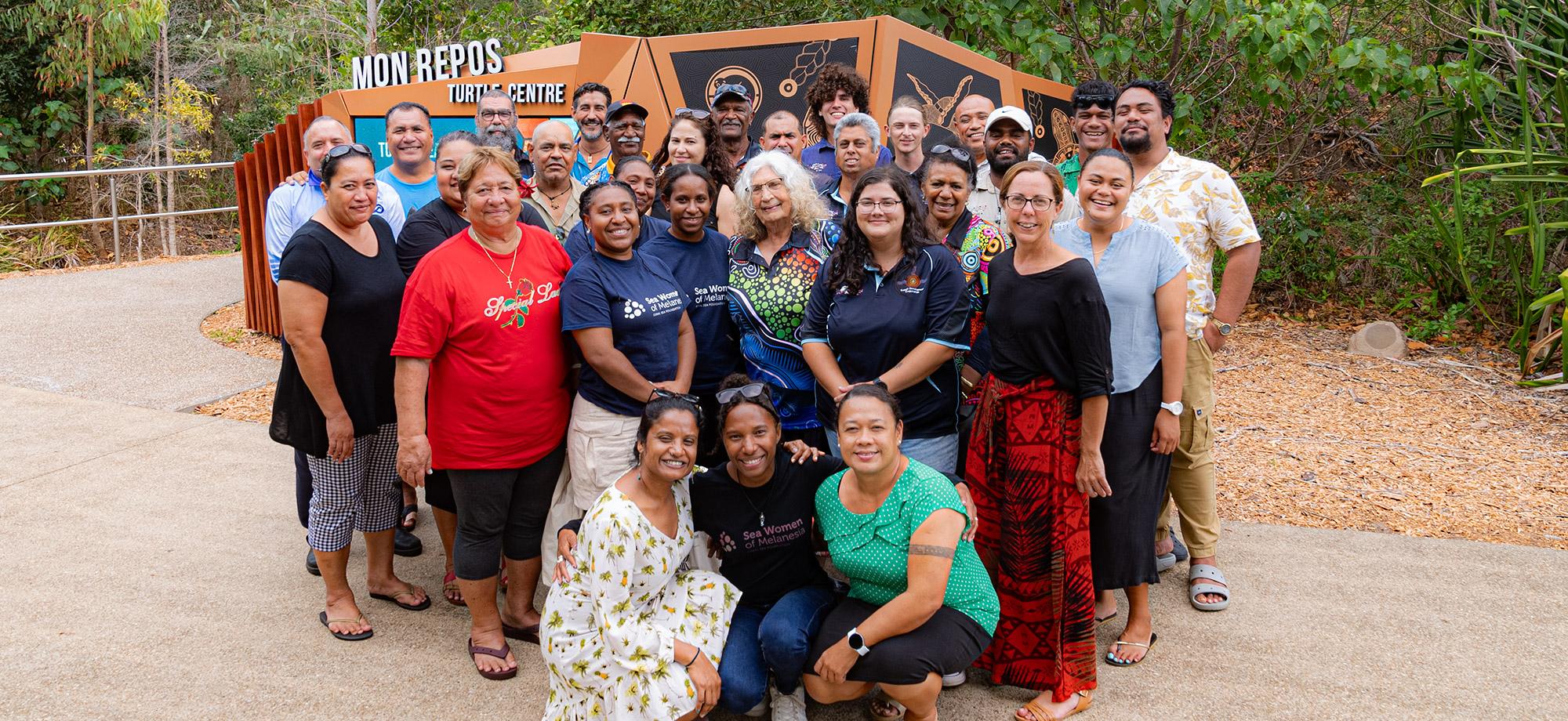 Group of people stand infront of a sign at Mon Repos