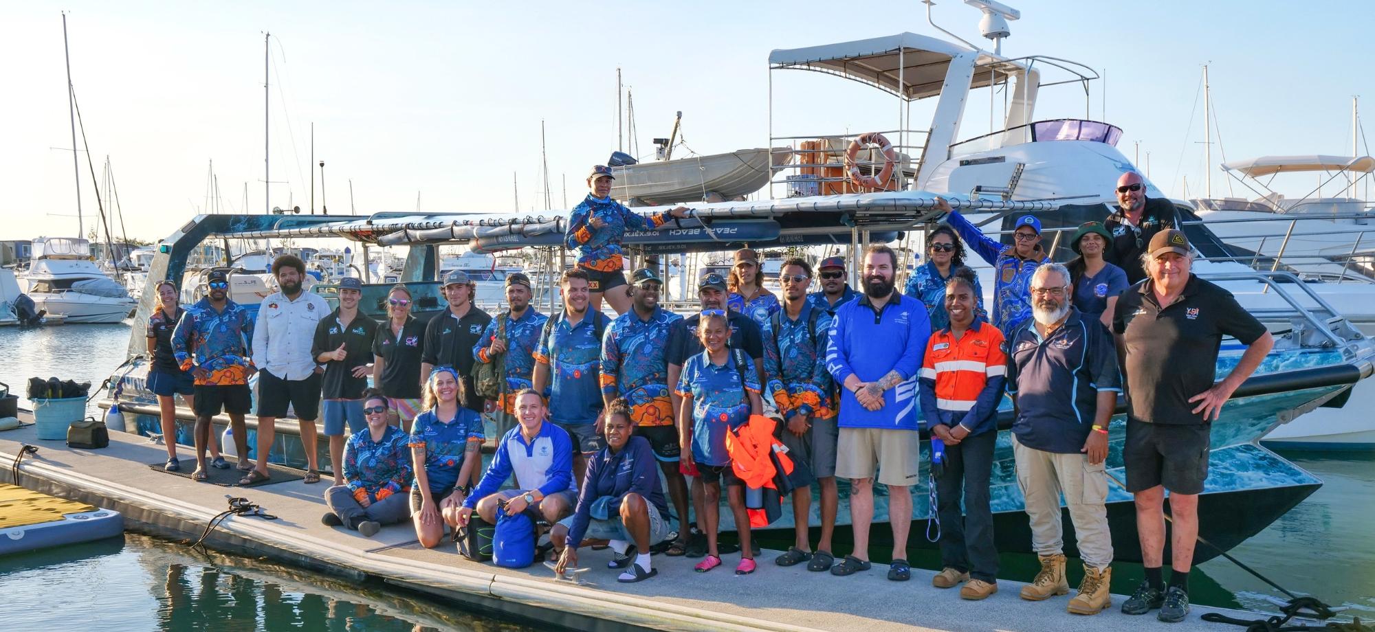 Indigenous Rangers and scientists in group photo in front of a boat