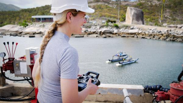 Person with helmet and remote control with large surface drone in background