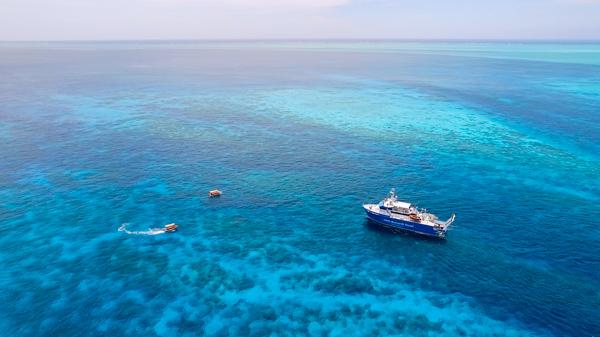 aerial photo on coral reef with large vessel and smaller orange tender