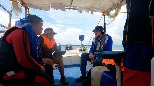 people sit on a small vessel with a reefscan attached to the back of the vessel
