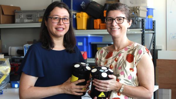 Two women hold devices that measure ocean currents