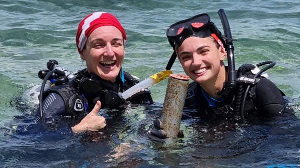 Two divers at the surface smiling and holding equipment that measure light
