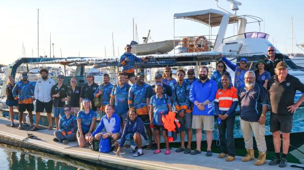 Indigenous Rangers and scientists in group photo in front of a boat