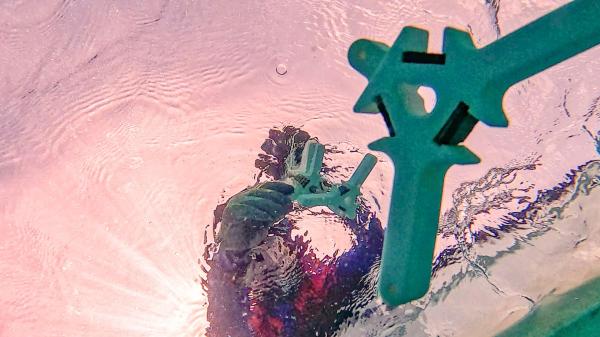 Underwater shot looking up at coral seeding devices being deployed from a boat.
