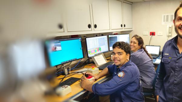 Three people posing in a control room of a science ship