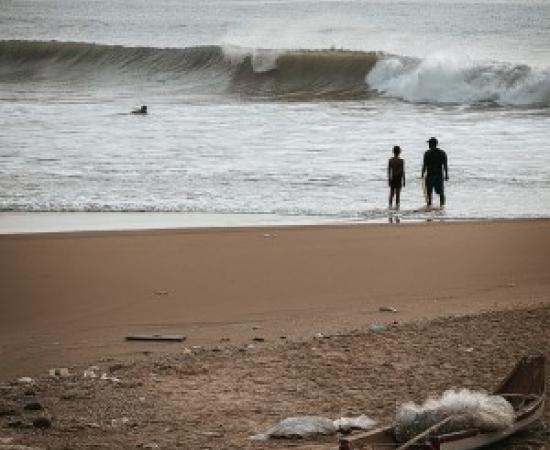 silhouette of two people on beach with rubbish in the foreground