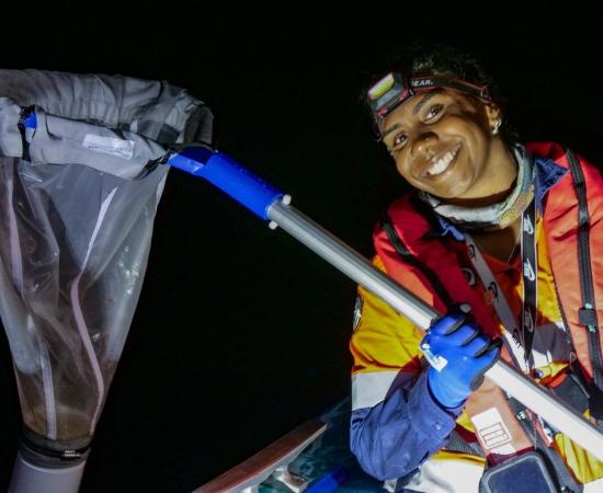Indigenous Ranger with net at sea at night