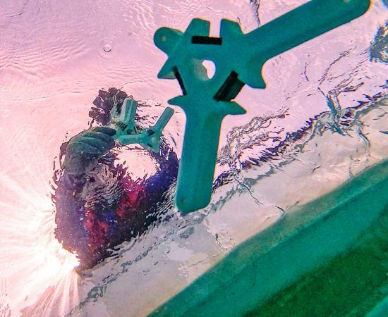 Underwater shot looking up at coral seeding devices being deployed from a boat.