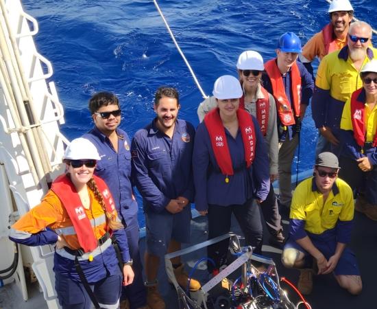 Marine science crew pose on back deck of research vessel
